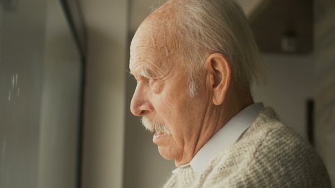 Elderly senior man stay at home on quarantine. Pensive looking away and feel upset. Sad grandfather widower alone. Thoughtful melancholy older retired gray haired grandpa. Sorrow grief loneliness conc