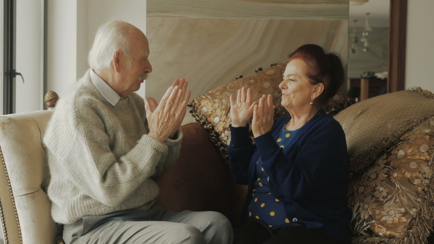 Happy elderly couple playing pat a cake. (Patting cake)