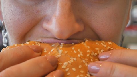 Girl eating a hamburger. close-up shot. Fast food eats. Burger in female hands.