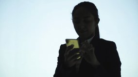 Cheerful businesswoman talking by smartphone. Silhouette of happy young business woman talking by cell phone on blue background. Connection concept