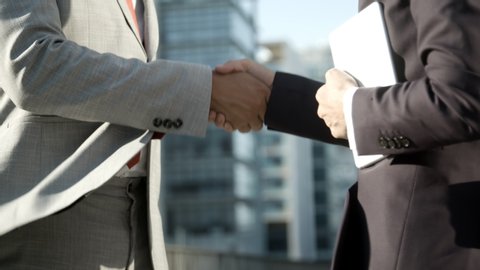 Side view of business consultants meeting outdoor. Closeup shot of colleagues shaking hands on street. Business handshake concept