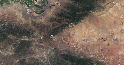 Very high-altitude overflight aerial of farmland and mountains SE of Bakersfield, California. Clip loops and is reversible. Elements of this image furnished by NASA