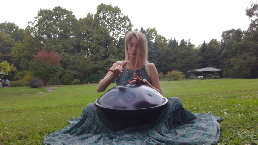 Popular, modern hang musical instrument in the hands of a beautiful blonde in an autumn park.