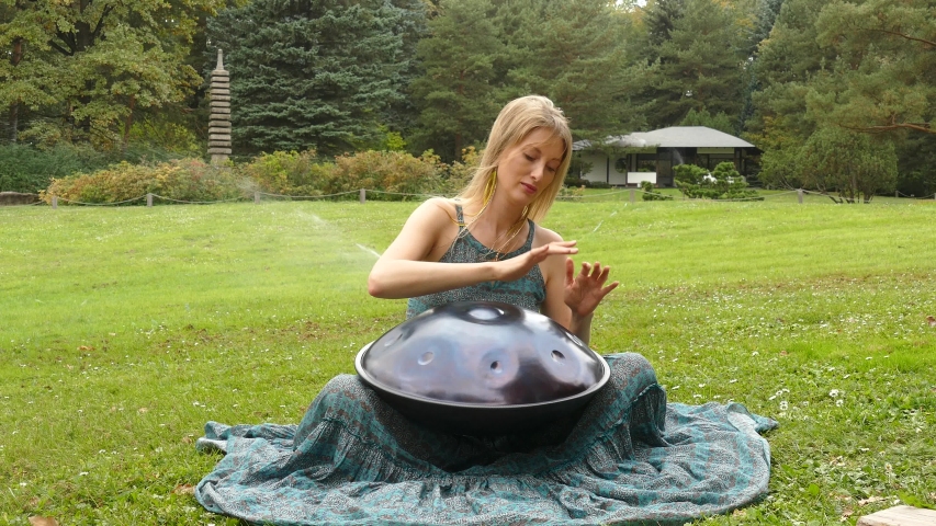 Popular, modern hang musical instrument in the hands of a beautiful blonde in an autumn park.