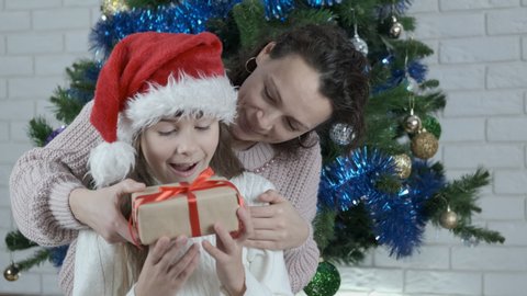 Mother presenting a Christmas gift. Little happy girl gets a gift. Mother gives her daughter a Christmas present.