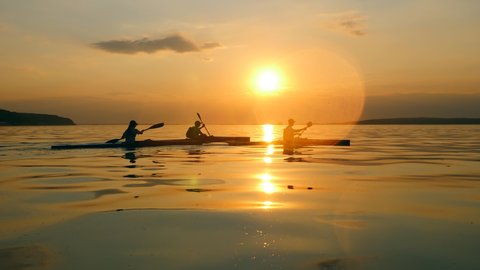 Boaters are kayaking at sunset in a side view