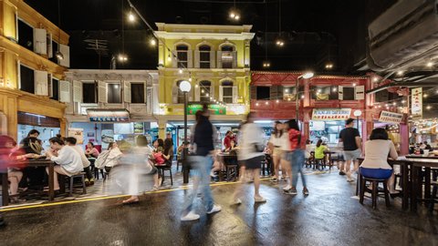 Singapore, Sentosa Island, 06-10-2019,  TL/time lapse of people eating at a crowded night market, food court, artificial indoors street scene, showing traditional architecture and traditional culture