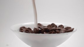 Chocolate corn flakes are falling in slow motion to the white bowl, cocoa cereal breakfast falls in 240fps, slow mo food, Full HD 10 bit uncompressed