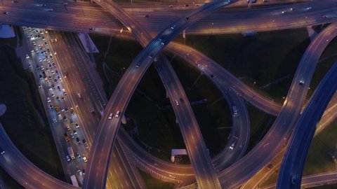 Aerial highway interchange intersection junction with ramps busy urban traffic cars speeding on road at night. Modern metropolis life. Europe Asia. Drone around details