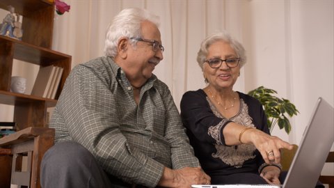 Happy Indian grandparents doing a video chat using laptop with their family. 4K stock footage of happy Indian parents watching their favorite movie on the laptop and enjoying - Old couple