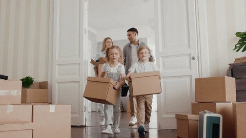 Happy Family Moves in New Home. Positive Looking at Relocating by Mom and Adult Dad with Furniture Packing in Modern Room. Casual Relax Child Emotion and Unpack by Small Son and Beautiful Daughter