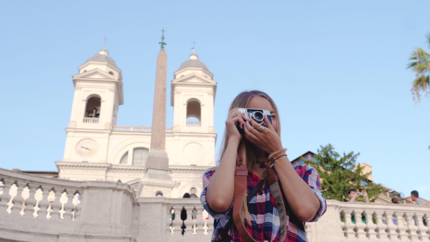 Young blond woman with vintage camera taking pictures at Spanish Steps in Rome, Italy.