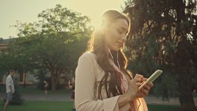 young woman listening music on smartphone in park