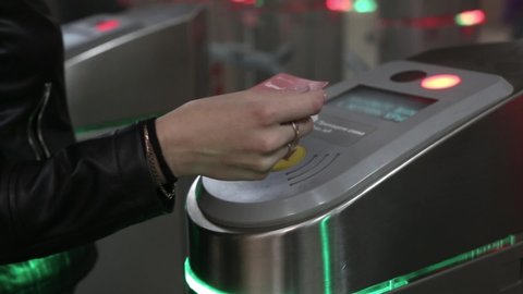 red and green light on subway turnstile. persons apply electronic touch card, people pass through opened doors. metro metal wicket control panel, paying for entrance