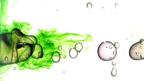 Close up and slow motion of pouring light colored oil from left side and creating a row of bubbles under water while bouncing around on white background, green ink flowing in at the end