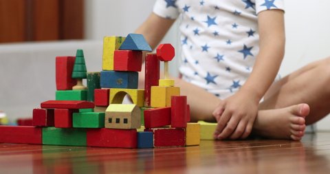 Toddler hands stacking wooden toy building blocks