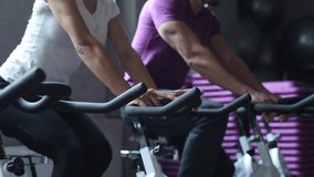 Attractive woman and man biking in the gym, exercising legs doing cardio workout cycling bikes. Couple in a spinning class wearing sportswear. Fitness healthy lifestyle concept - Powered by Shutterstock - Get 15% off with code: PIKWIZARD15