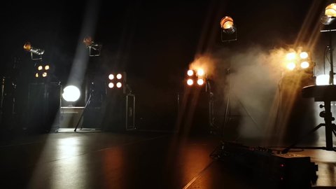 Close-up video of a concert stage and lighting fixtures on it. smoke from a smoke installation gently breaks yellow light and creates the effect of a gentle glow.