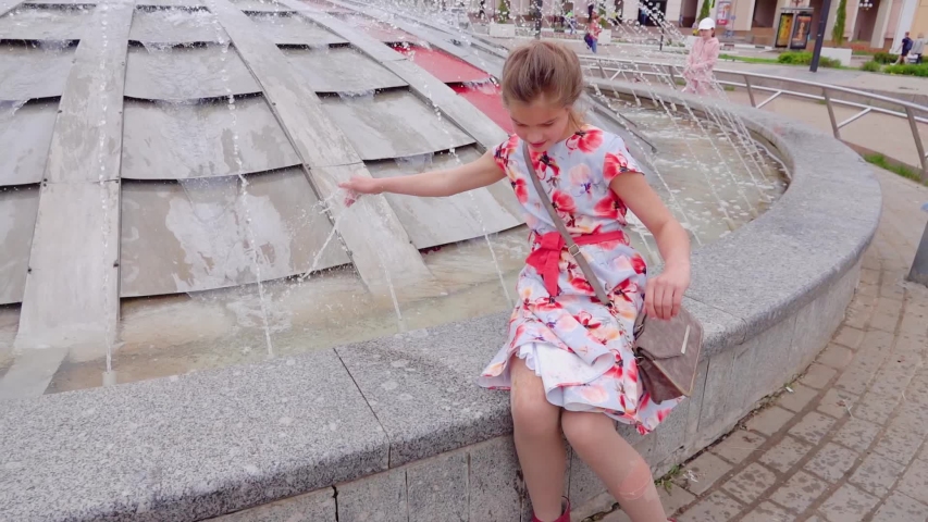 Little beautiful girl is played by a fountain in the city square in Dmitrov, Moscow region, Russia.