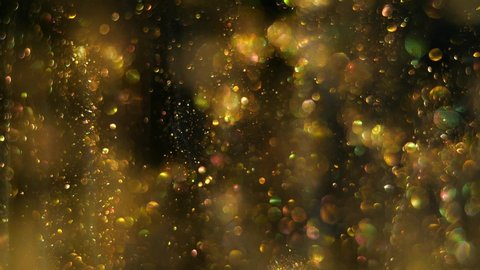 Magical tiny round blurred golden particles glittering, moving slowly and randomly on the black space background.