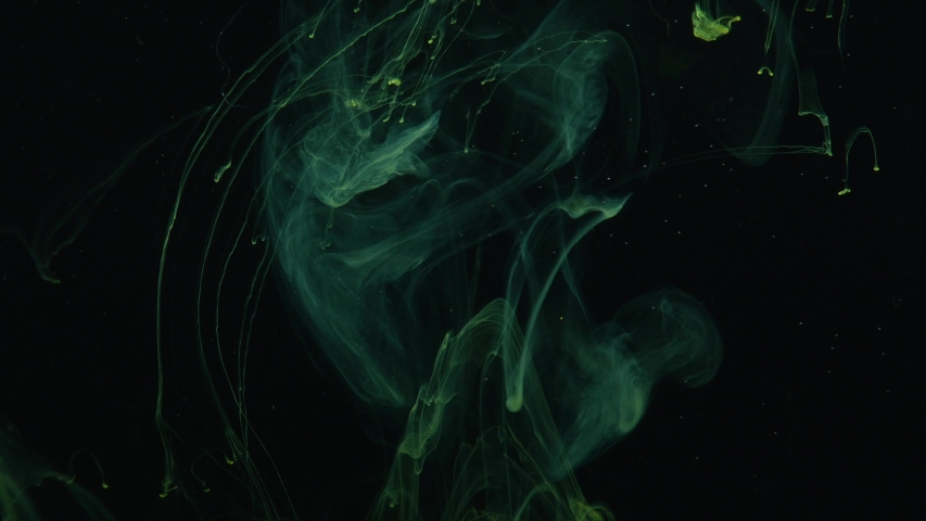 Stream of yellow light smoke appearing on the black background, waving and curling mysteriously. Sapce behing it full of small particles.