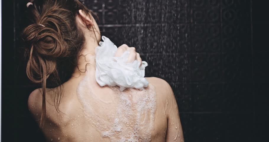Woman taking shower in slow motion. Filmed in 4K DCi resolution. Young beautiful woman taking a shower and gently touching her skin, washing her back. Beauty and wellbeing concept.