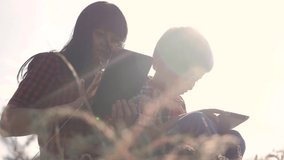 happy family concept. Mother and son slow motion video. Mom and son with digital tablet work and play in the final light flare outdoors.