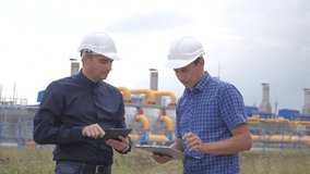 teamwork. industry gas production station concept. slow motion video. two engineers in helmets are studying working lifestyle with a digital tablet in a factorygas supply business contract. two