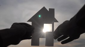 happy family house construction concept. man holding home a paper house in lifestyle his hands at sunset silhouette sunlight. life ecology video symbol