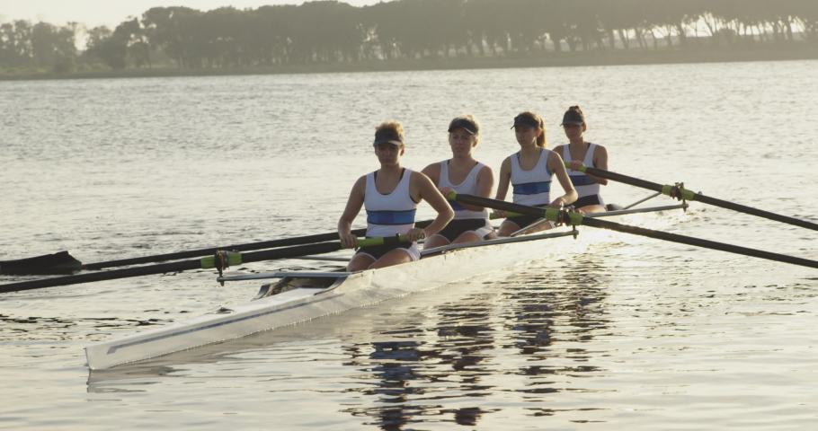 Front view of a team of four young adult Caucasian women rowing in a racing shell on a river