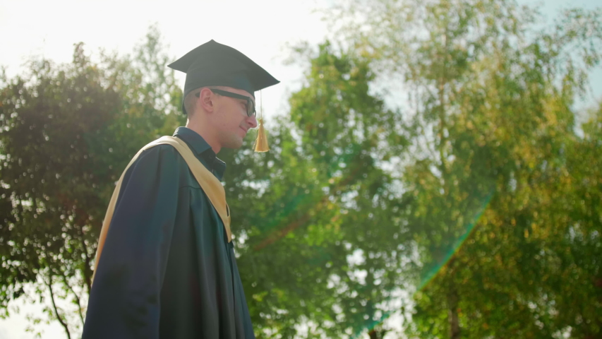 Excited Graduate Student in Gown and Cap with Diploma Hugs his Friend after Graduation Ceremony. 4K Slow Motion Medium Close-Up Shot with Beautiful Sun Lens Flare Royalty-Free Stock Footage #1037560829