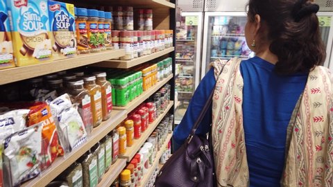 Pune , Maharashtra / India - 06 02 2019: Young Indian Lady is Shopping at a Grocery Shop and Browsing through Various Products