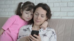 Family with a smartphone. A woman with a child looking at the screen of a smartphone.