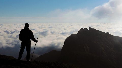 Climber on the top of Serra dos Órgãos with clouds passing in the background