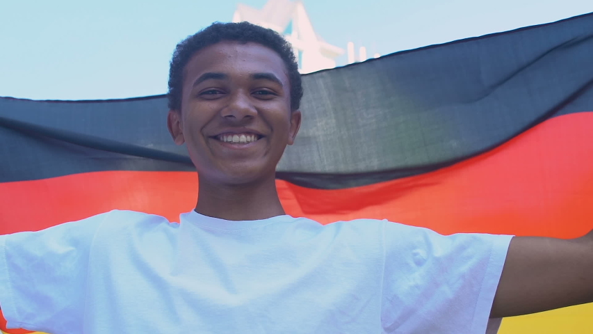 Afro-American teenager boy waving German flag outdoors, national holiday
