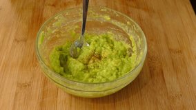 Pouring spices, chili pepper, paprika, oregano, in a glass bowl full of guacamole, full hd, 24fps