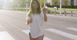 Medium shot of a woman dancing seductively in the street during sunset with lensflare - shot on RED
