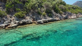 The turquoise and clear water of the Mediterranean Sea. Stone ruins on the coast of Turkey. Aerial video shooting.