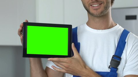 Smiling male in workwear holding prekeyed tablet, online repairman service