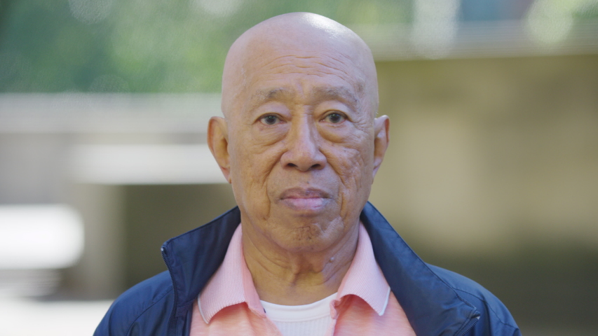 Portrait of Senior elderly Asian male looking to camera and smiling, in slow motion