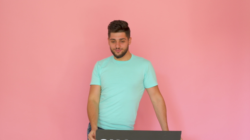 handsome funny smiling guy with shopping sign dancing isolated over pink