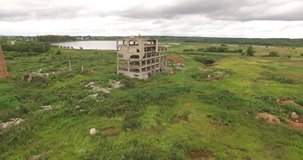 4K aerial summer cloudy day drone video of abandoned dilapidated industrial building ruins with red brick chimney located by small lake and green field in the middle of countryside