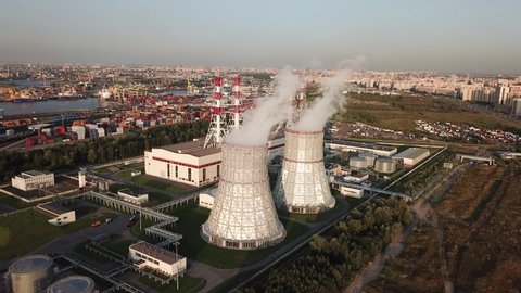 4K summer afternoon aerial drone video of new modern thermal power station, electricity producing plant, huge cooling water towers, located on outskirts of large city in northern hemisphere
