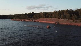 4K summer late afternoon aerial video of Santalahti Baltic Sea Finnish Bay lagoon, pine tree forest beach with red granite boulders, lone island beach near Kotka, Finland Suomi, northern Europe