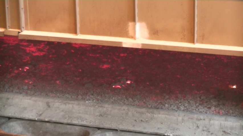 Large furnace with molten red metal. Bright sparks and lights. Heat.