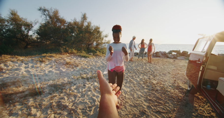 Slow motion of group of young multi-ethnic friends just arrived with a minivan are having fun to start a vacation on a beach with a sea on a sunset. Royalty-Free Stock Footage #1037631296