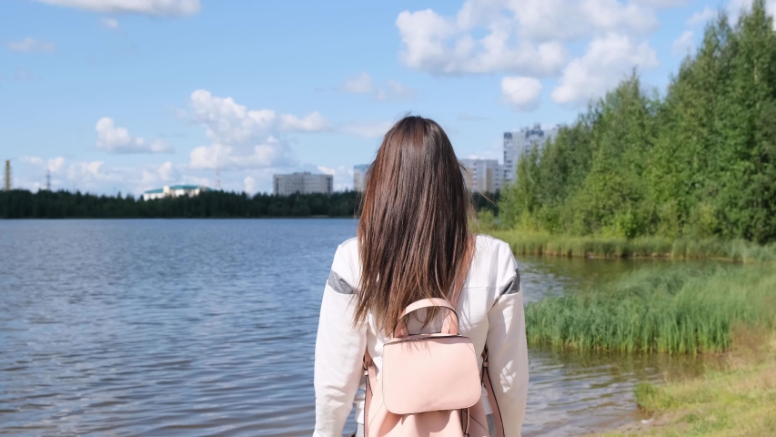 Girl with open hands. Freedom of nature. A girl stands enjoying the beautiful sunshine. A girl stands near the water in the open air. Young woman thinks about something