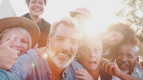 POV Shot Of Group Of Mature Friends Posing For Selfie At Outdoor Campsite
