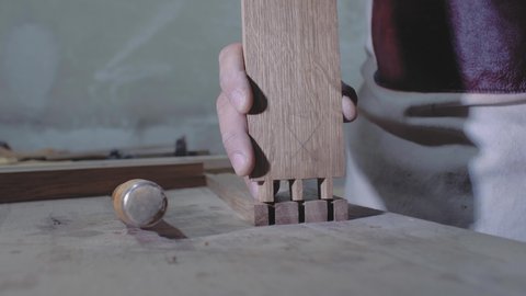 a carpenter joins two wooden parts made using the technology of a dovetail with a hammer. Detail of a carpenter with dovetail joints. 4k. 4k video. slow motion. 24 fps