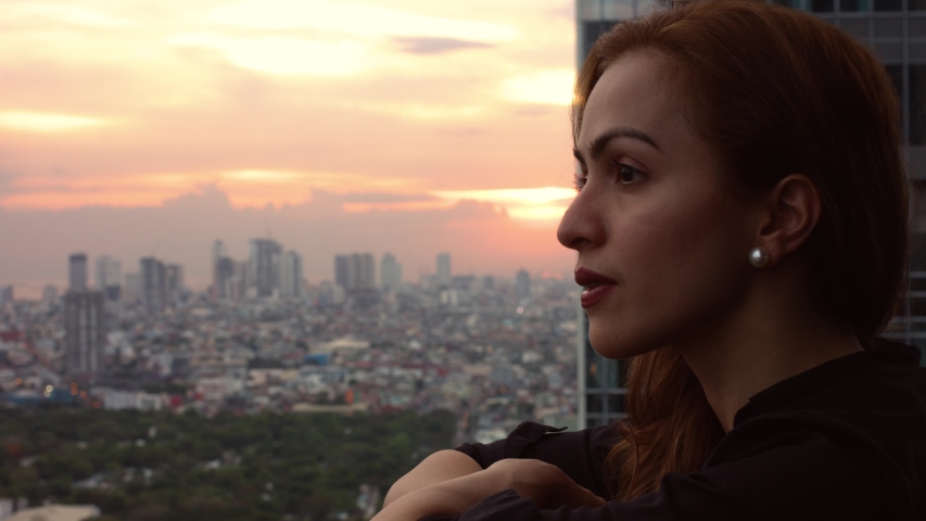 young red-haired woman watching the sunset over the city, Manila Philippines